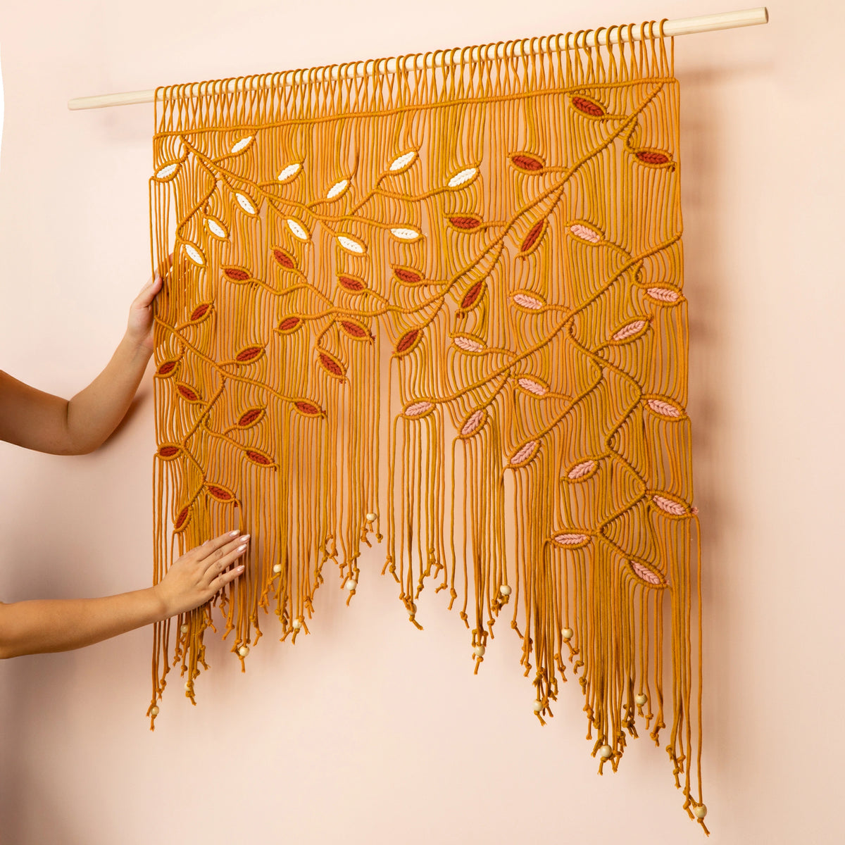 Handmade wall hanging with intricate patterns on a beige background