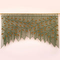 A decorative wall hanging or curtain made of many long green strands, arranged in a tree-like pattern with small orange leaf shapes and a gold rod across the top, shown against a pale pink background.