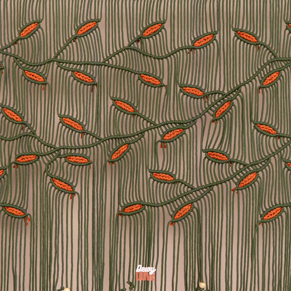 Large olive green and orange leaf macrame wall art hanging horizontally on a smooth wooden dowel above a modern wooden console table.