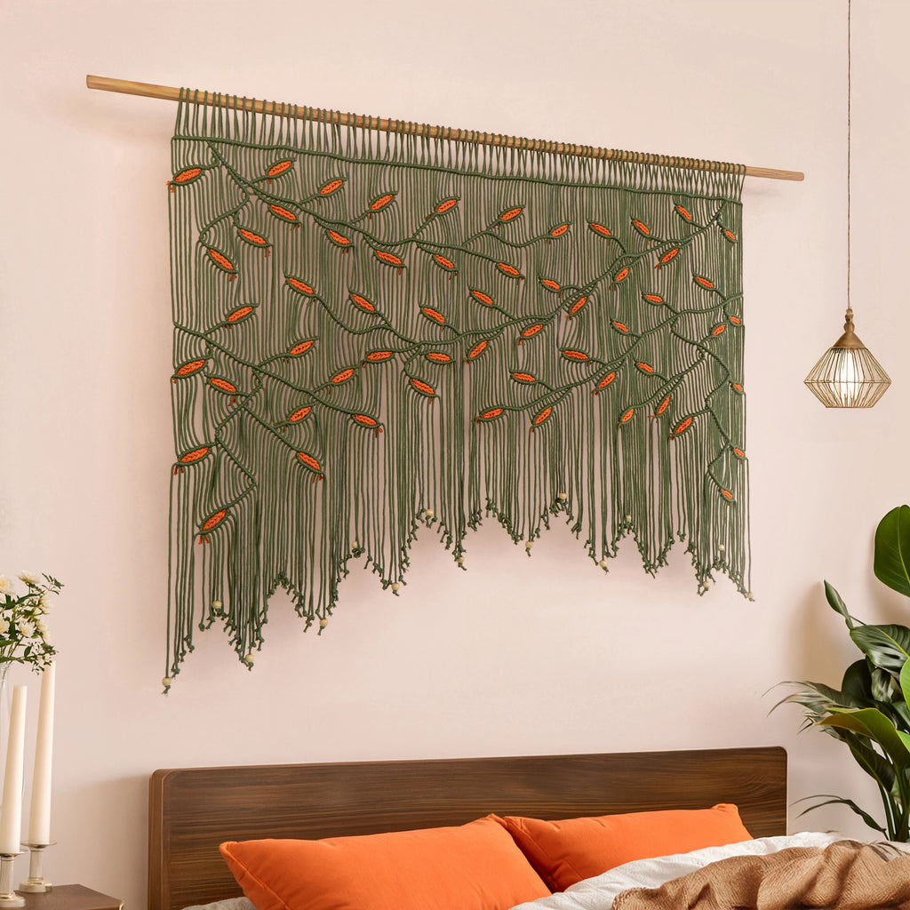 Wide botanical macrame tapestry showcasing an arched branch canopy in dark green with warm rust-orange leaf highlights.