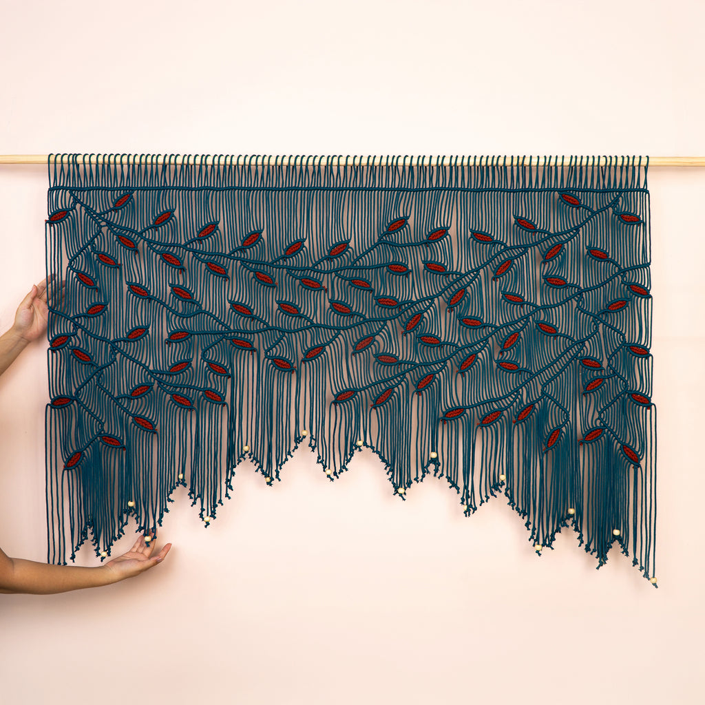 Large peacock teal macrame wall hanging with a wide botanical vine design and merlot red leaf accents.