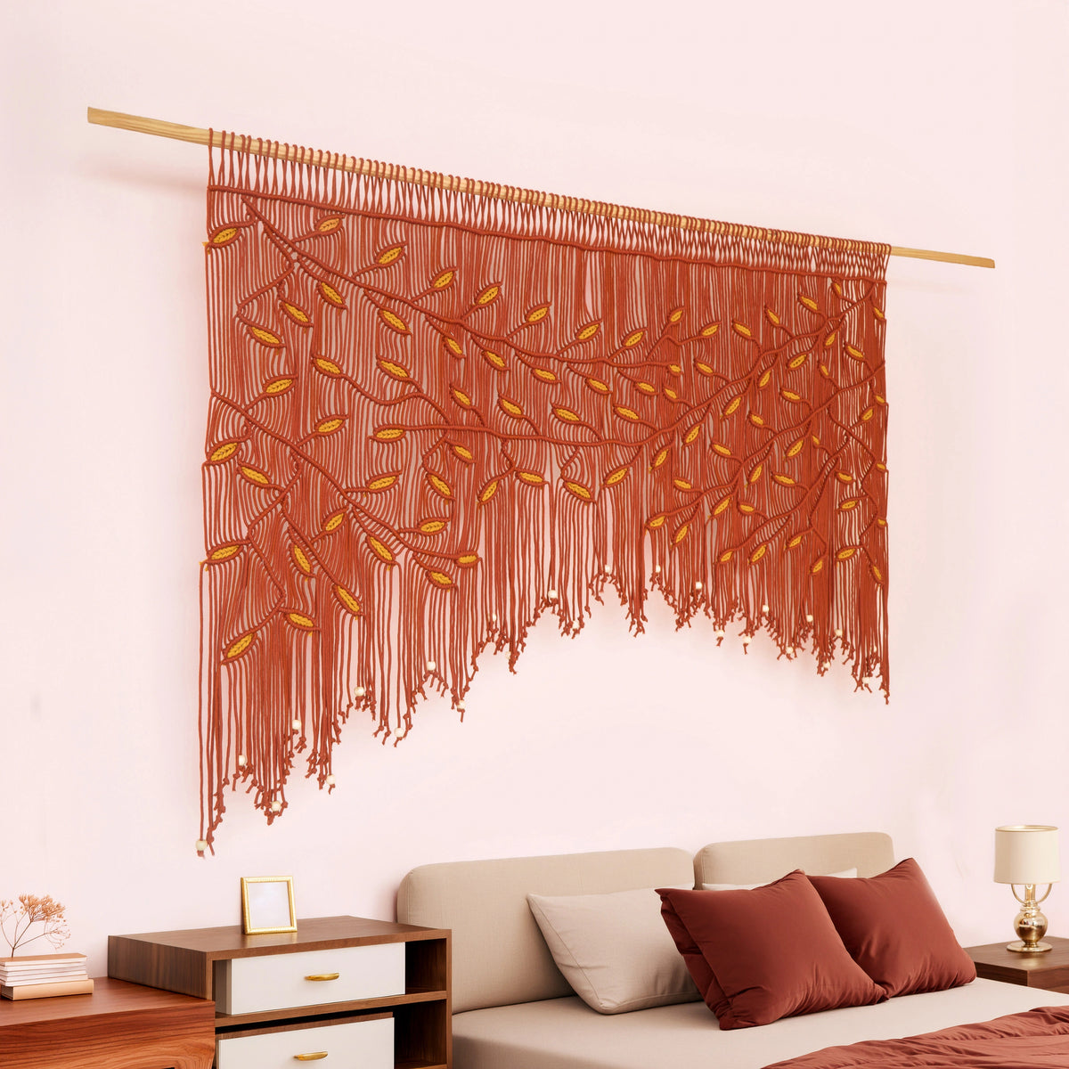 A large bohemian-style woven wall tapestry featuring a tree design in terracotta and mustard yellow, hanging on a light wood rod above a bed in a bedroom setting.