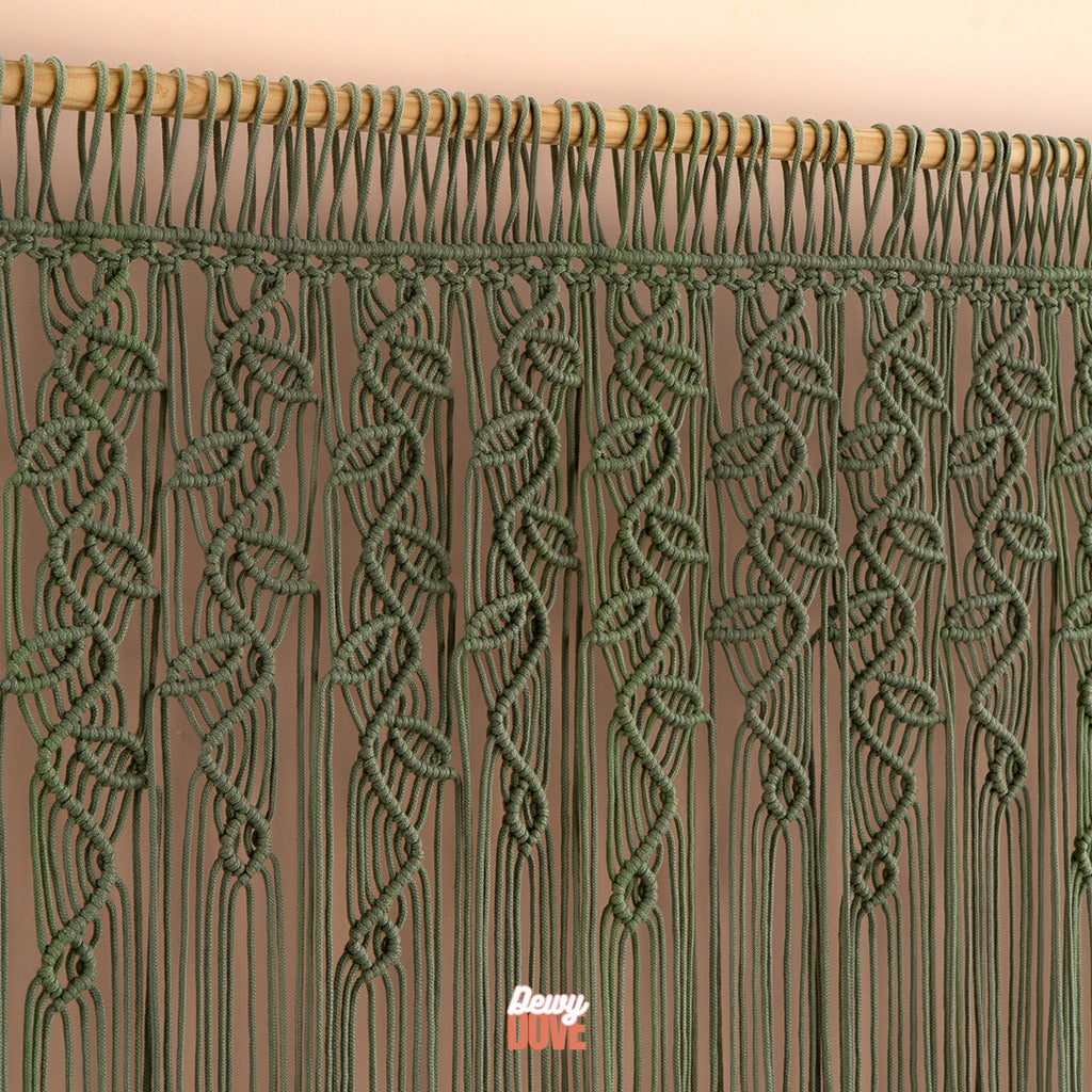 Green macrame curtain with wooden rod on a beige background