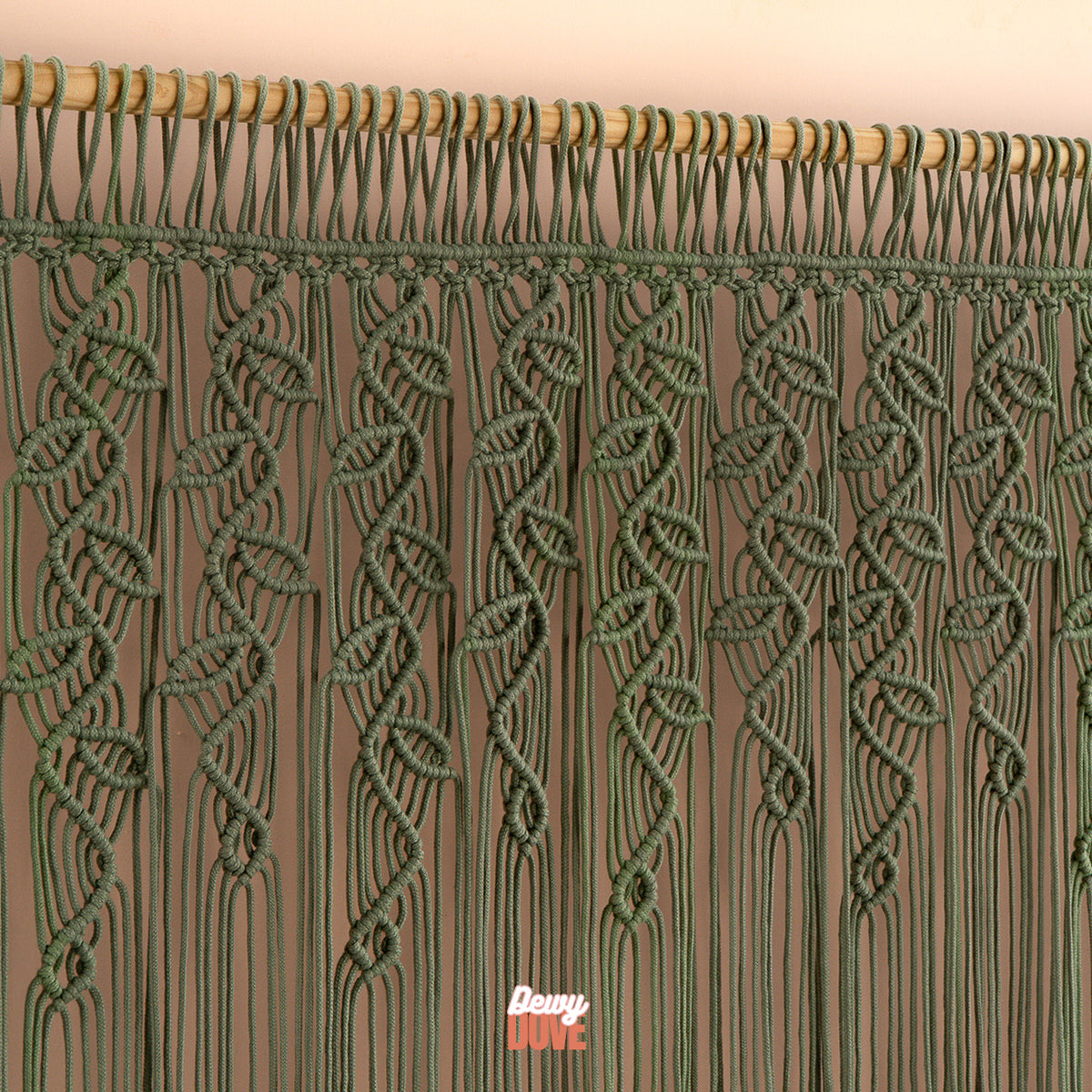Green macrame curtain with wooden rod on a beige background