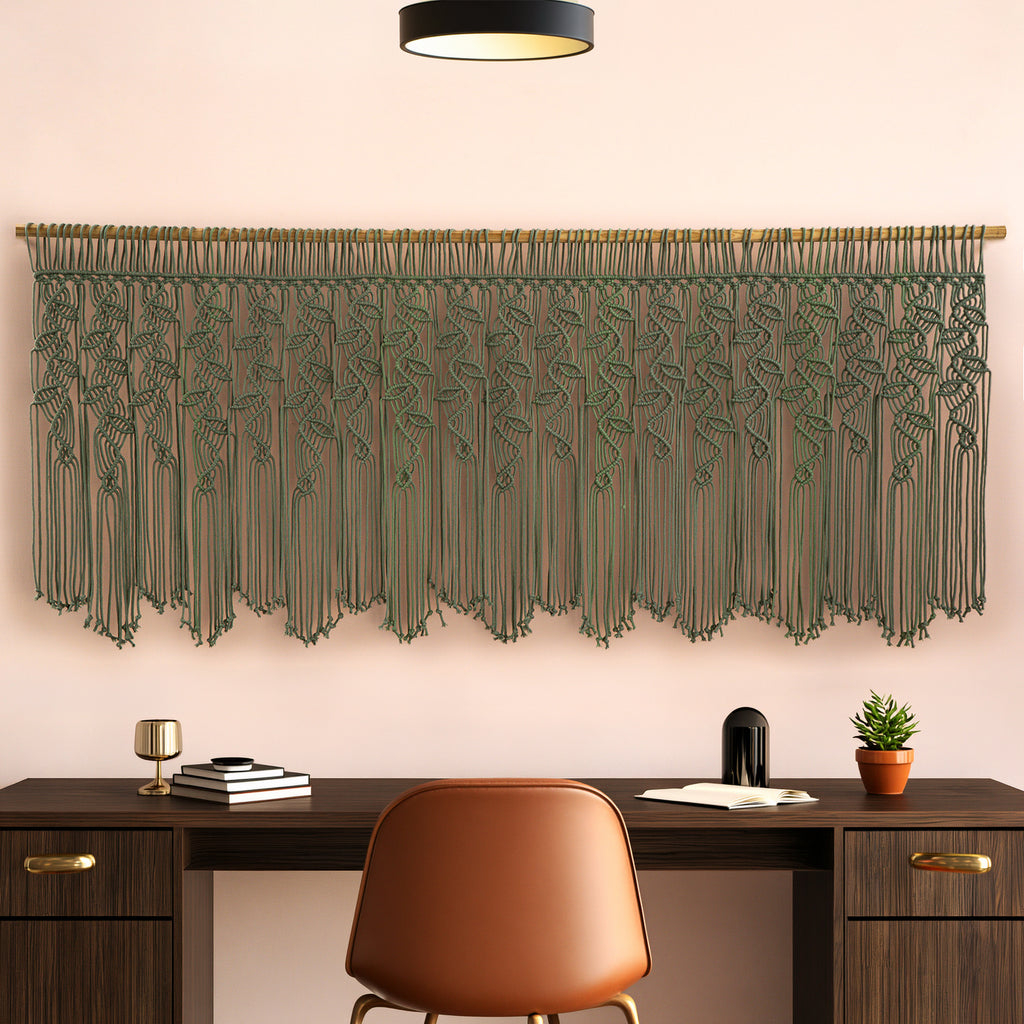 Decorative green macrame wall hanging above a wooden desk with a chair.