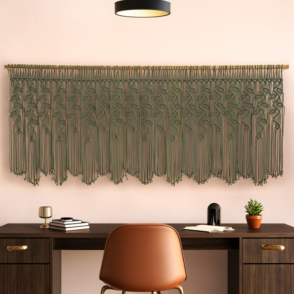 Decorative green macrame wall hanging above a wooden desk with a chair.